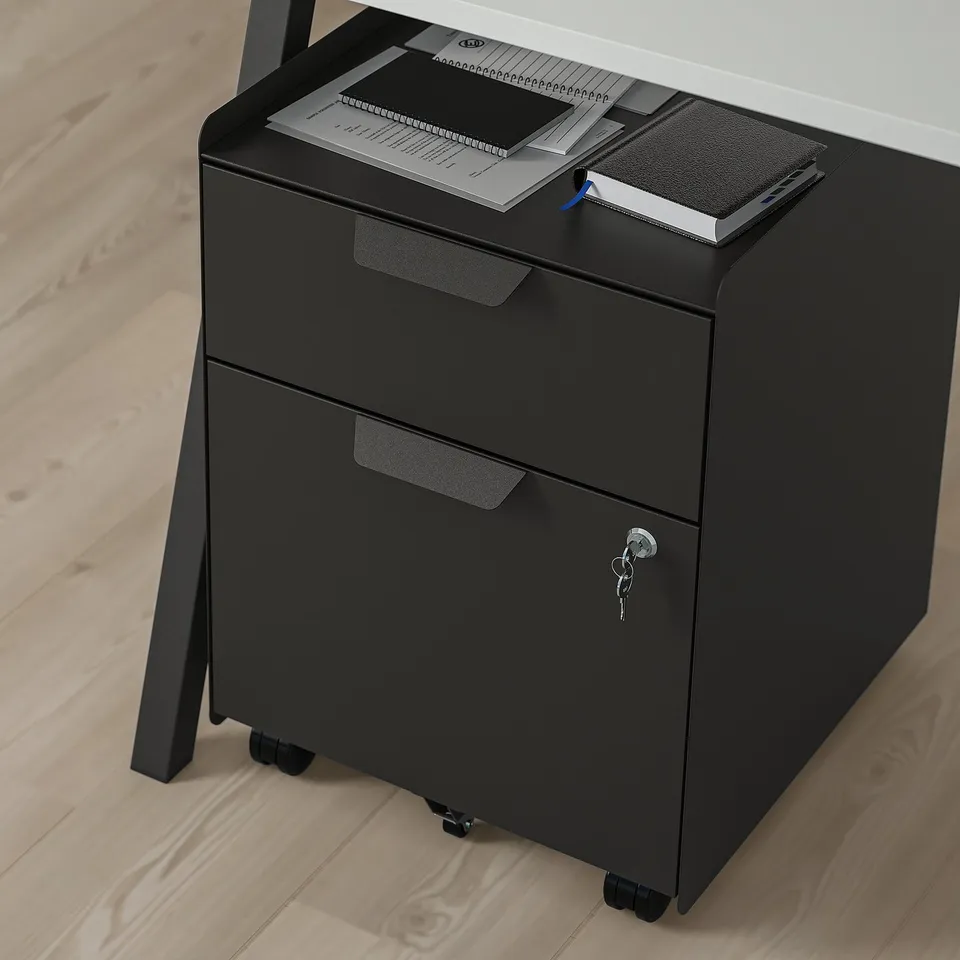 Black office cabinet with two drawers and a lock, placed under a desk on wheels.