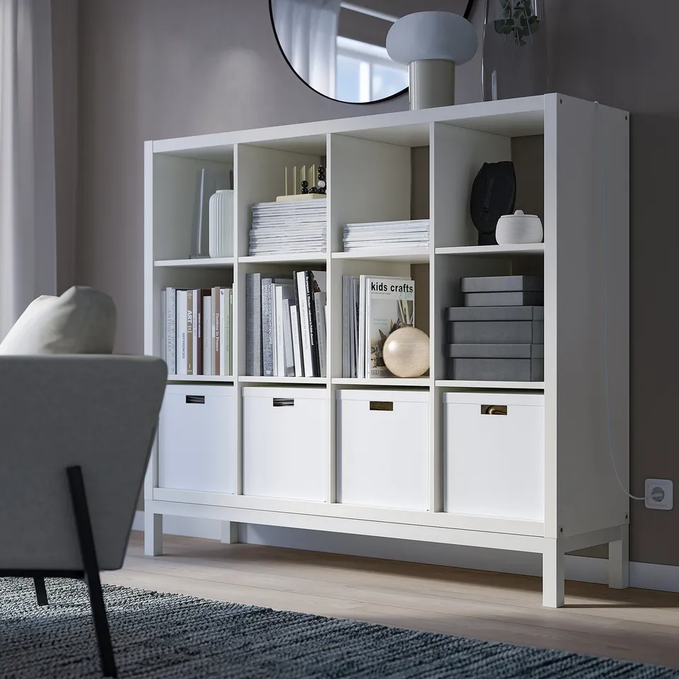 Modern white KALLAX bookshelf, large, with various items displayed, set against a grey wall.