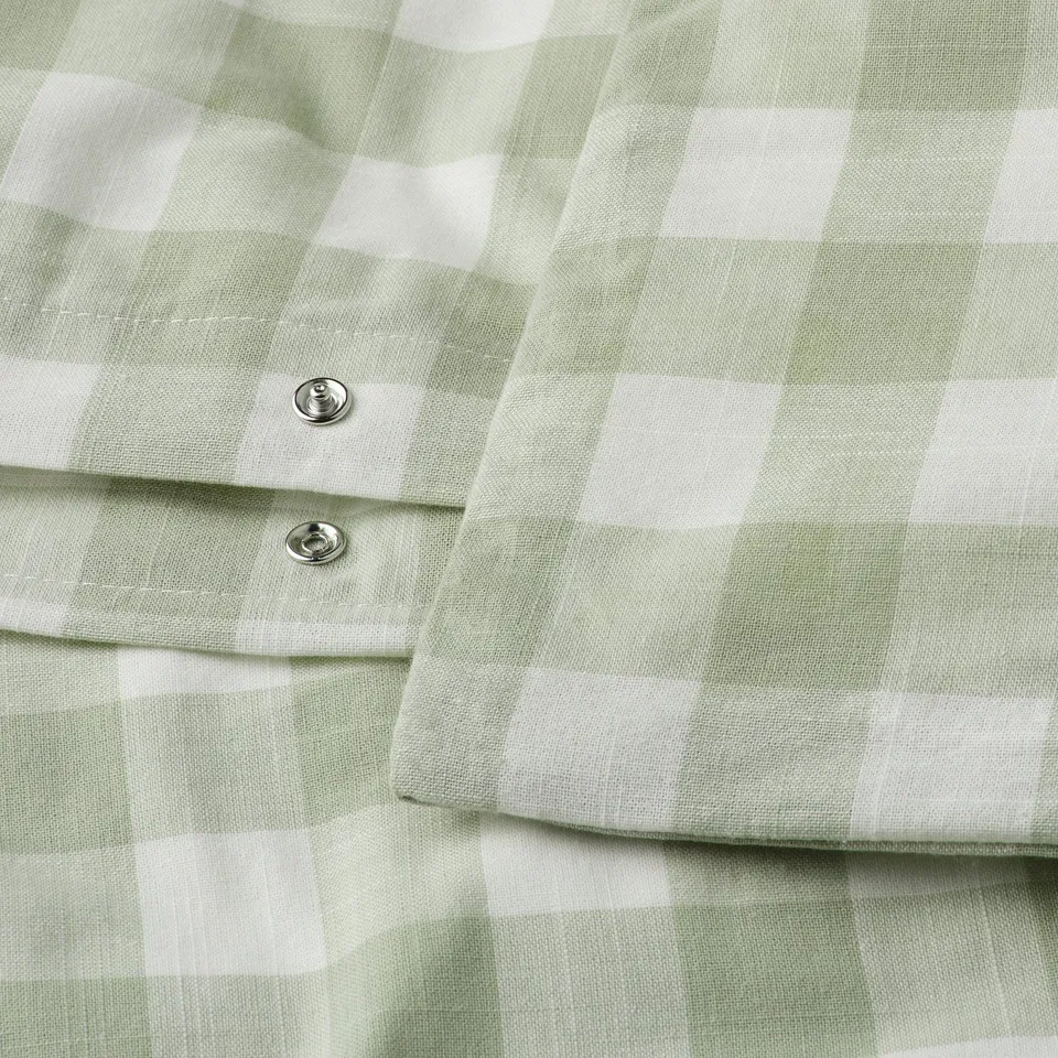Close-up of green and white chequered duvet cover with snap closures. Made of breathable organic cotton.