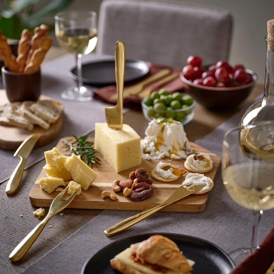 Cheese tools, knife & fork by cheeses, almonds, grapes, wine glasses.