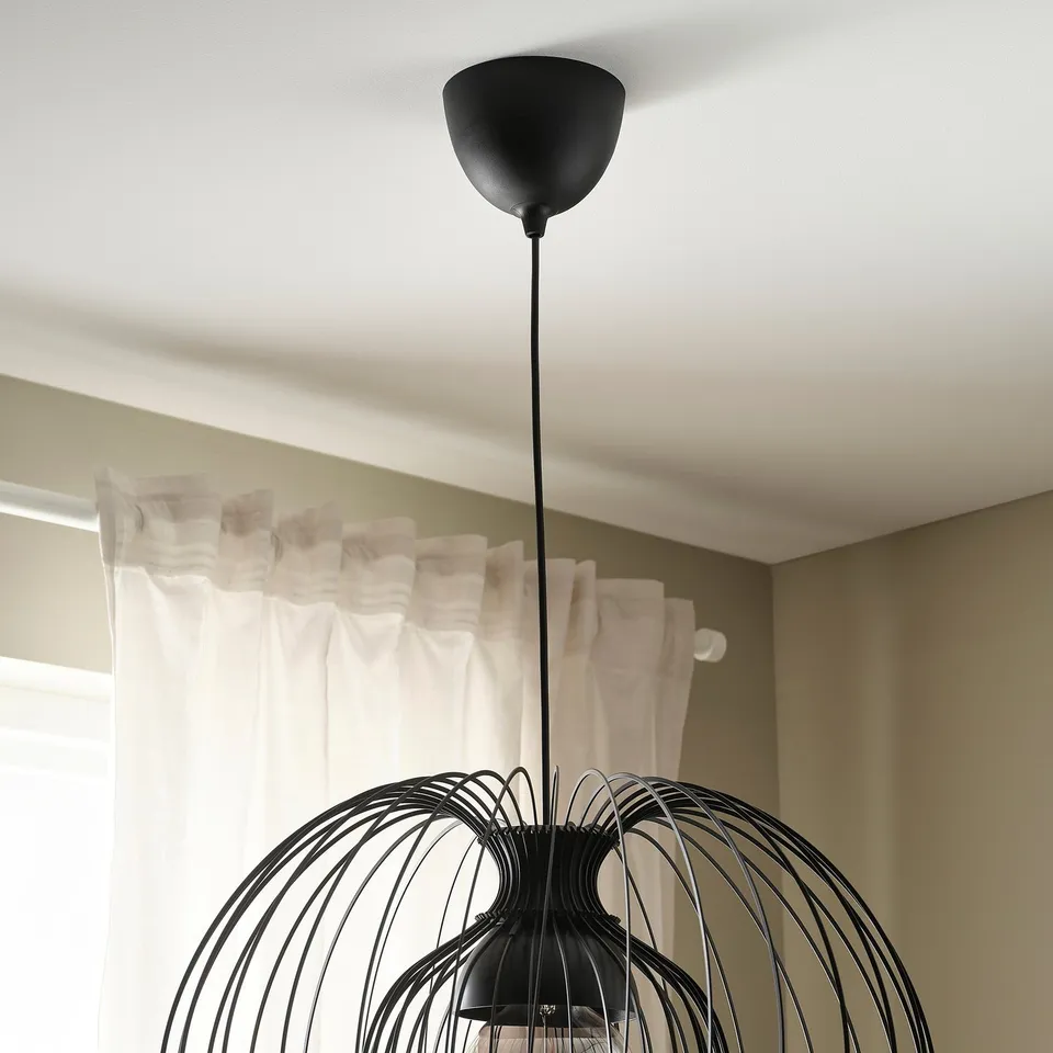 Modern pendant light with intricate, woven design hangs from ceiling, providing adjustable lighting.
