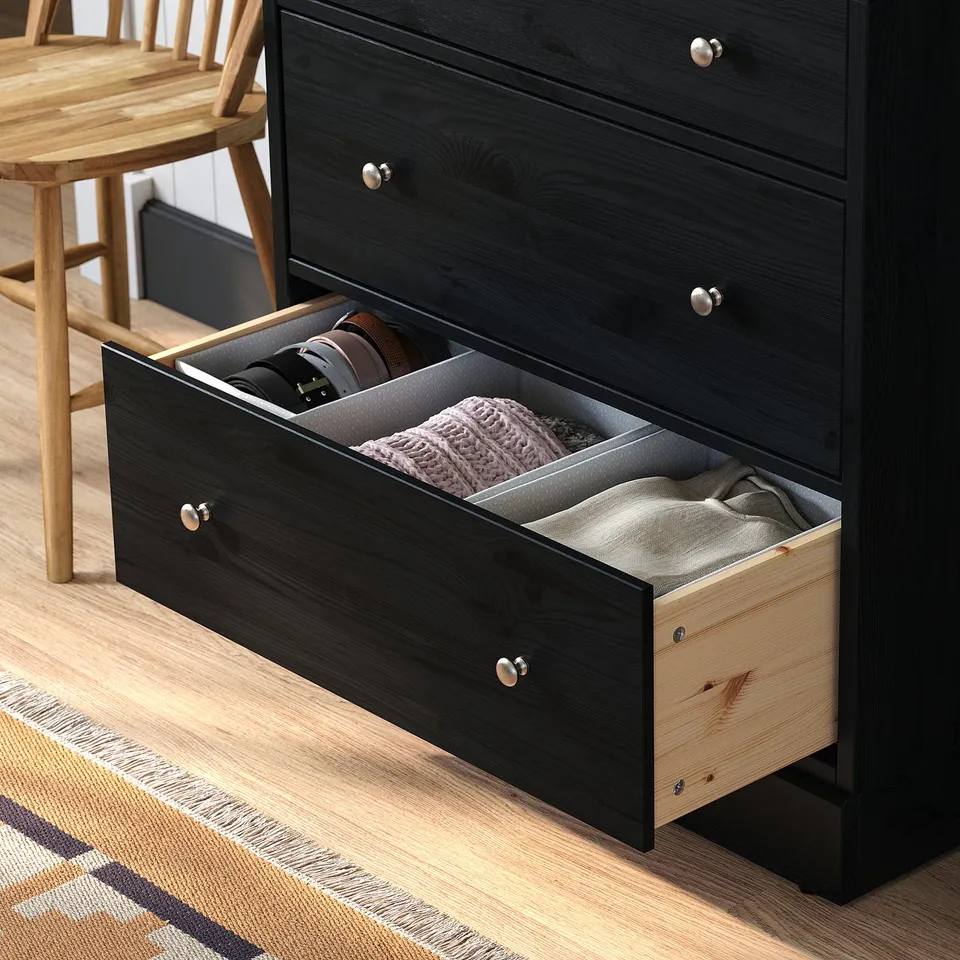 Black wooden chest of drawers with an open drawer revealing compartments and folded clothes. The drawer pulls out smoothly.