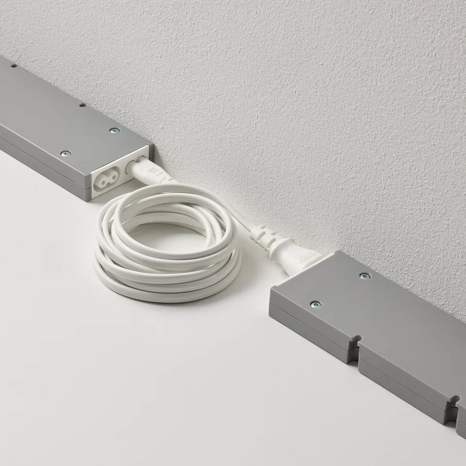 Two rectangular devices connected by a white cord for linking and controlling multiple lamps with a single power supply.