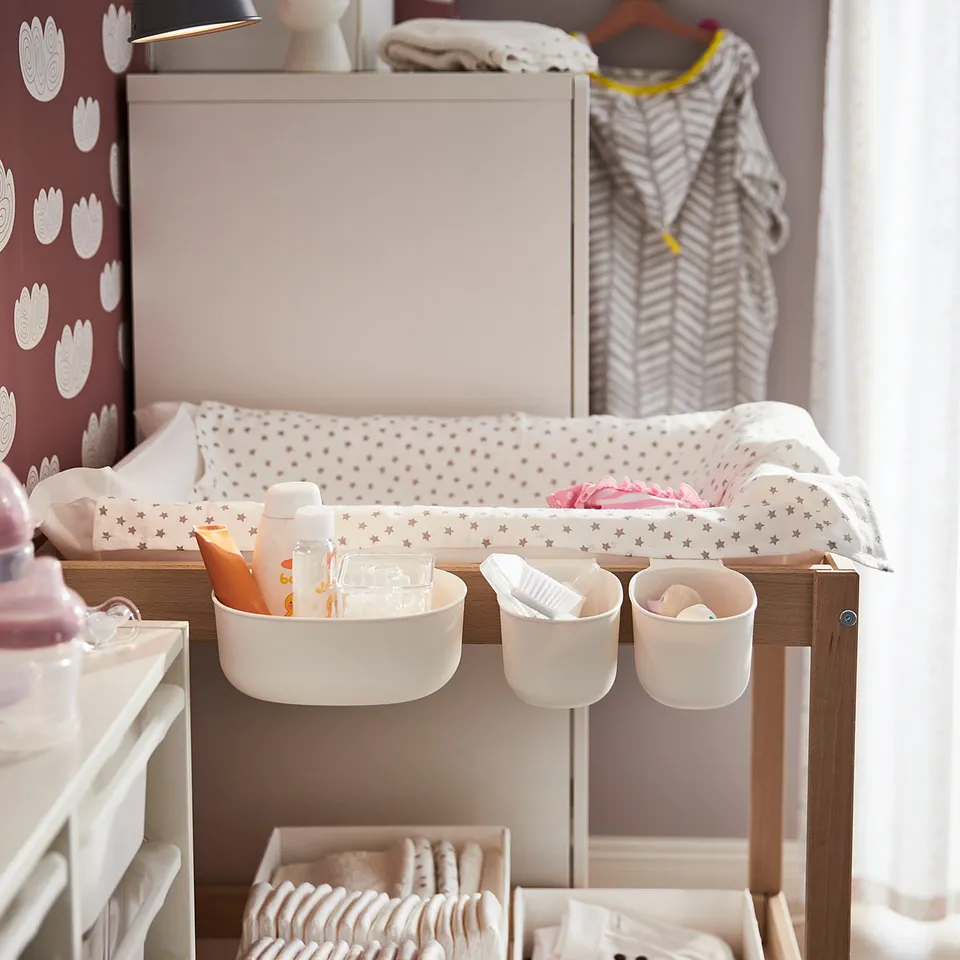 Baby changing table with drawers & hanging containers in nursery.