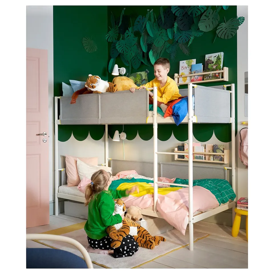 Two children playing on white VITVAL bunk bed with green wall and leaf decals. Boy on top, girl below, both with stuffed tigers.