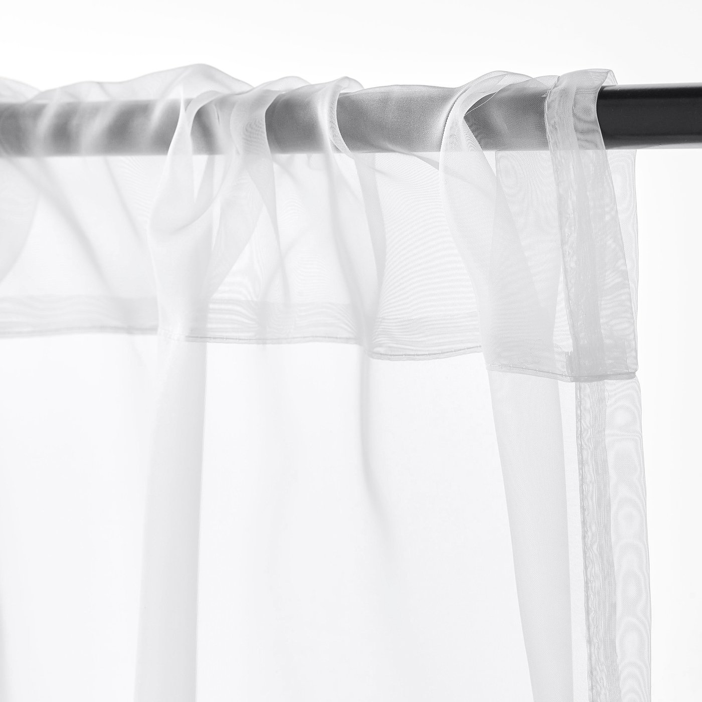 White sheer curtains with rod pocket, allowing daylight and privacy.