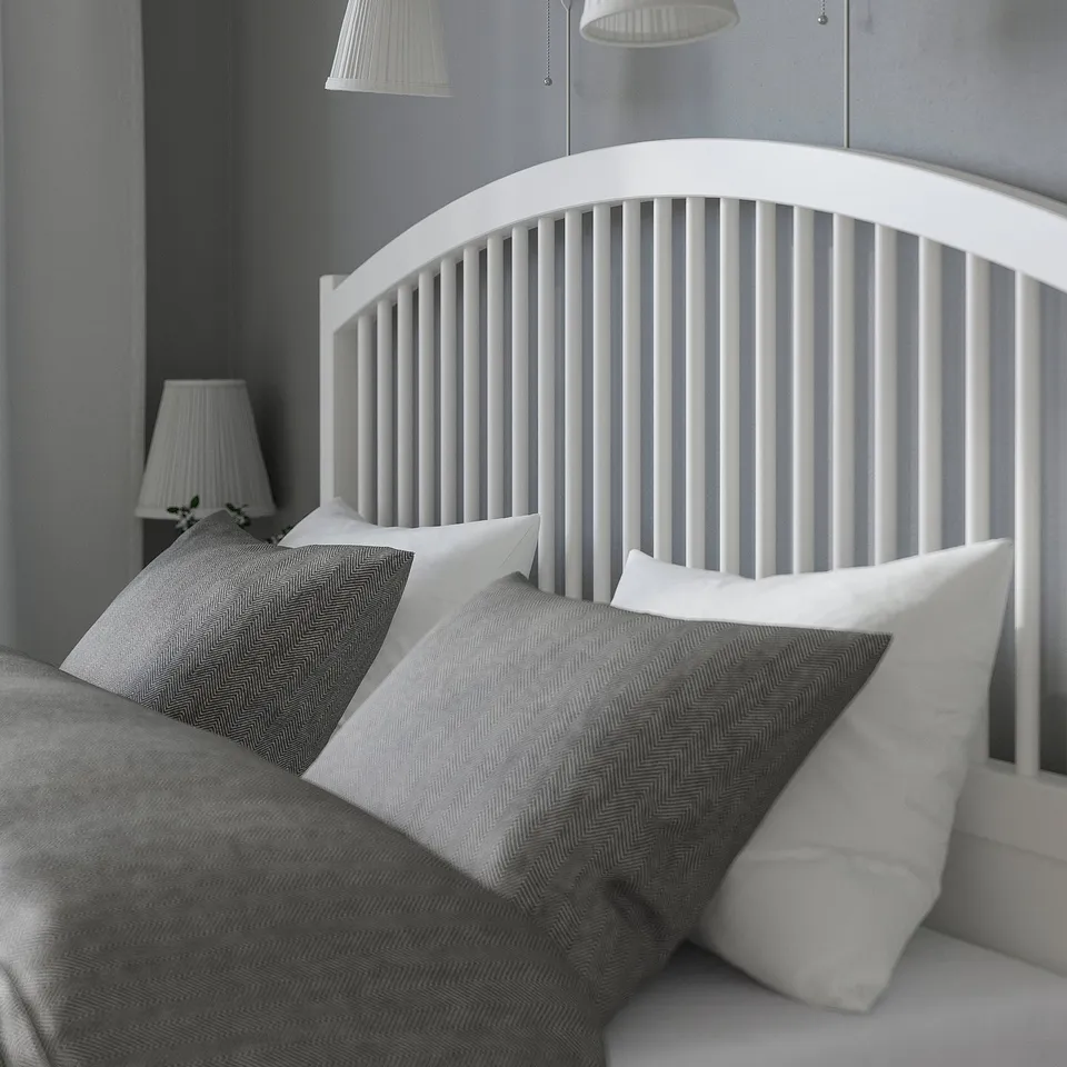 Black and white a modern bed with a high wooden headboard, two pillows, and a blanket, showcasing a clean and minimalistic bedroom setup.