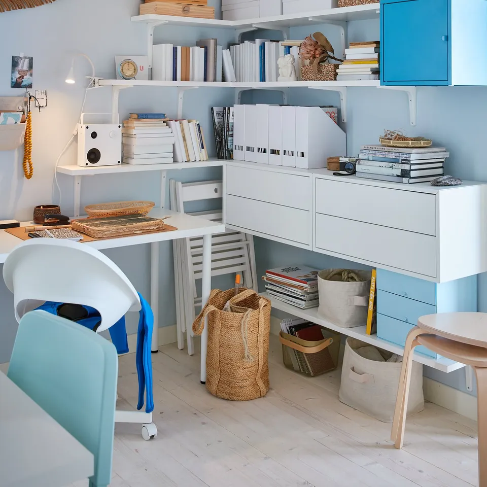 Cosy blue/white home office with books, decor, & wall shelves.