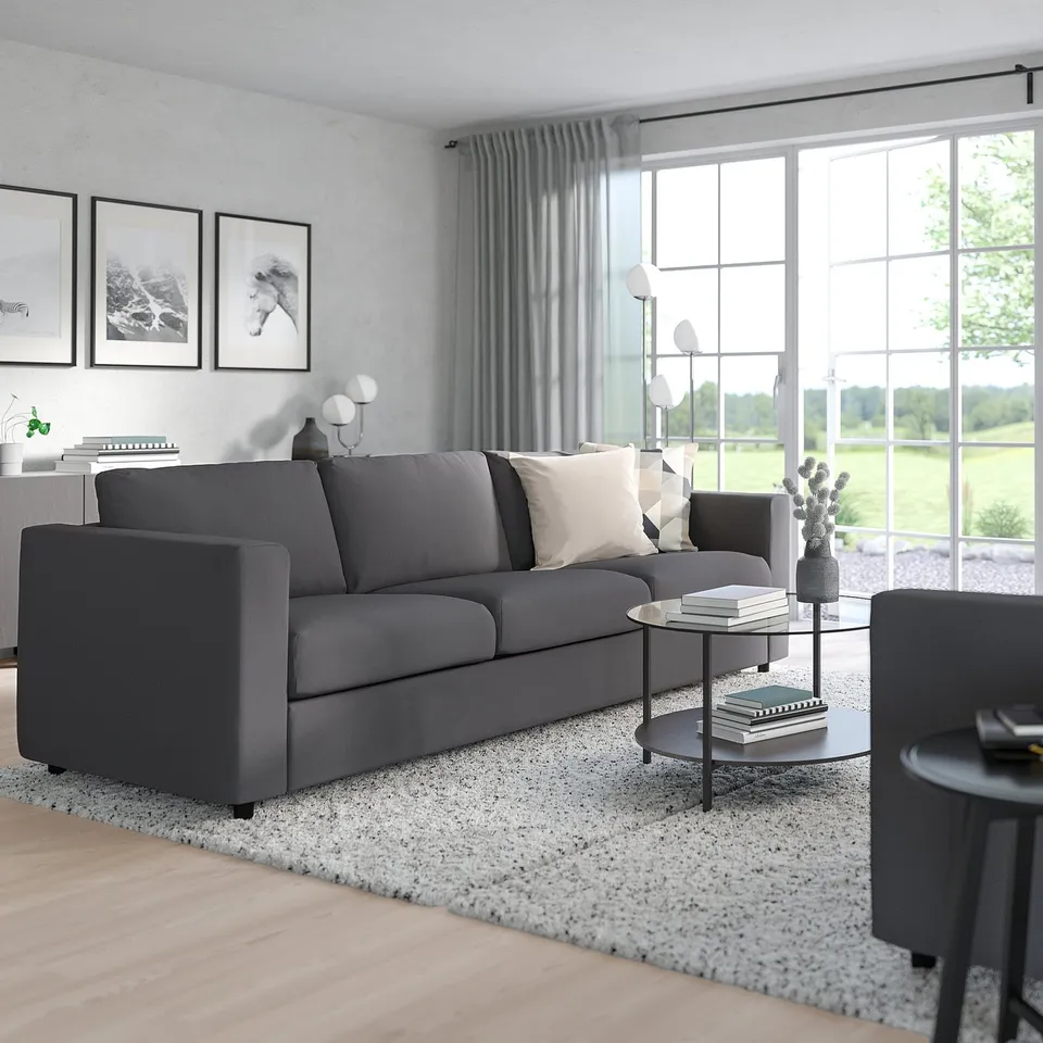 Modern living room with VIMLE charcoal sofa, glass coffee table, windows, and wall art.