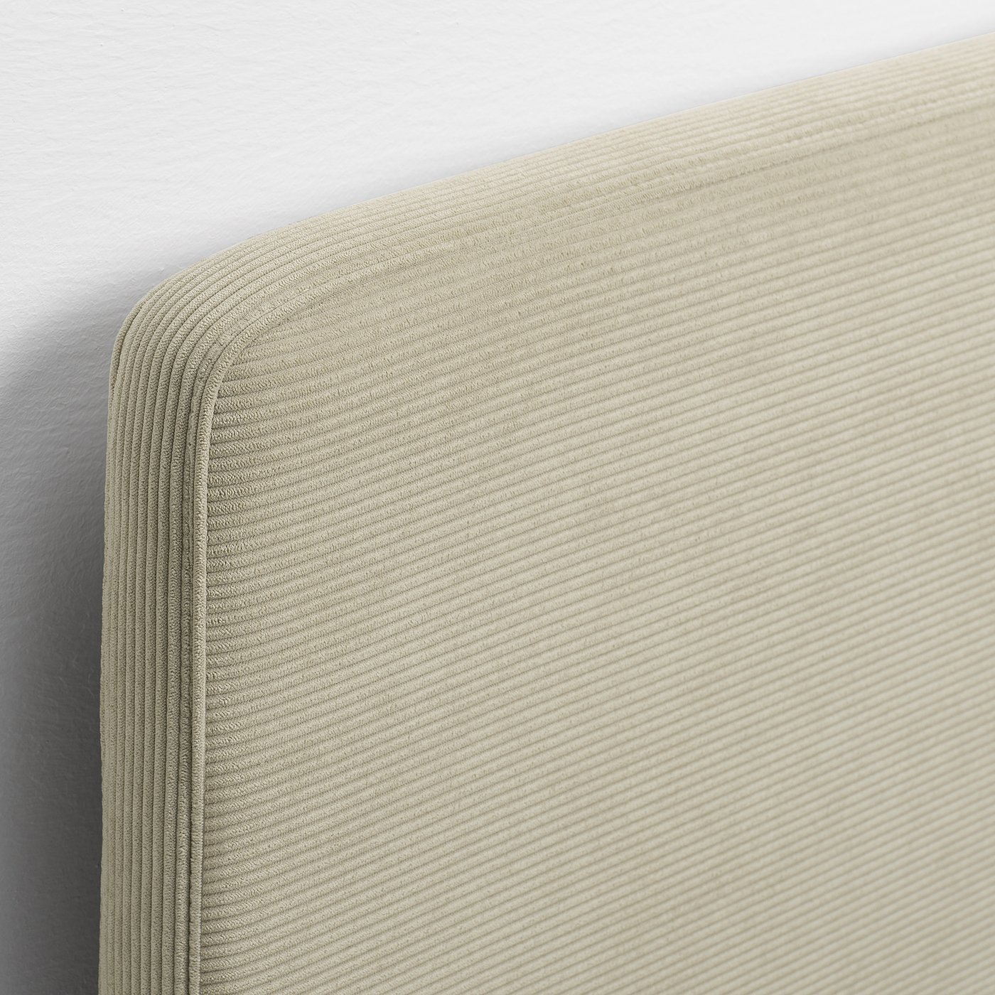Close-up of modern bed frame with beige, ribbed fabric headboard; soft, comfy texture and clean stitching.