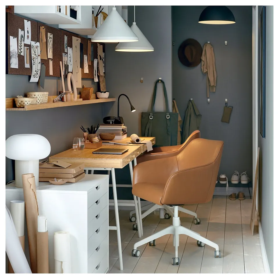 Home office with TOSSBERG leather chair, desk, lamp, and shelves with supplies.