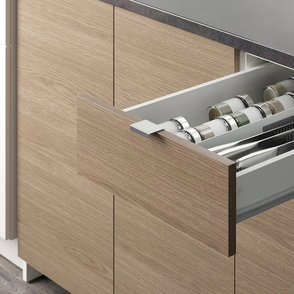 Kitchen drawer open showing spice jars, seamless wood finish.