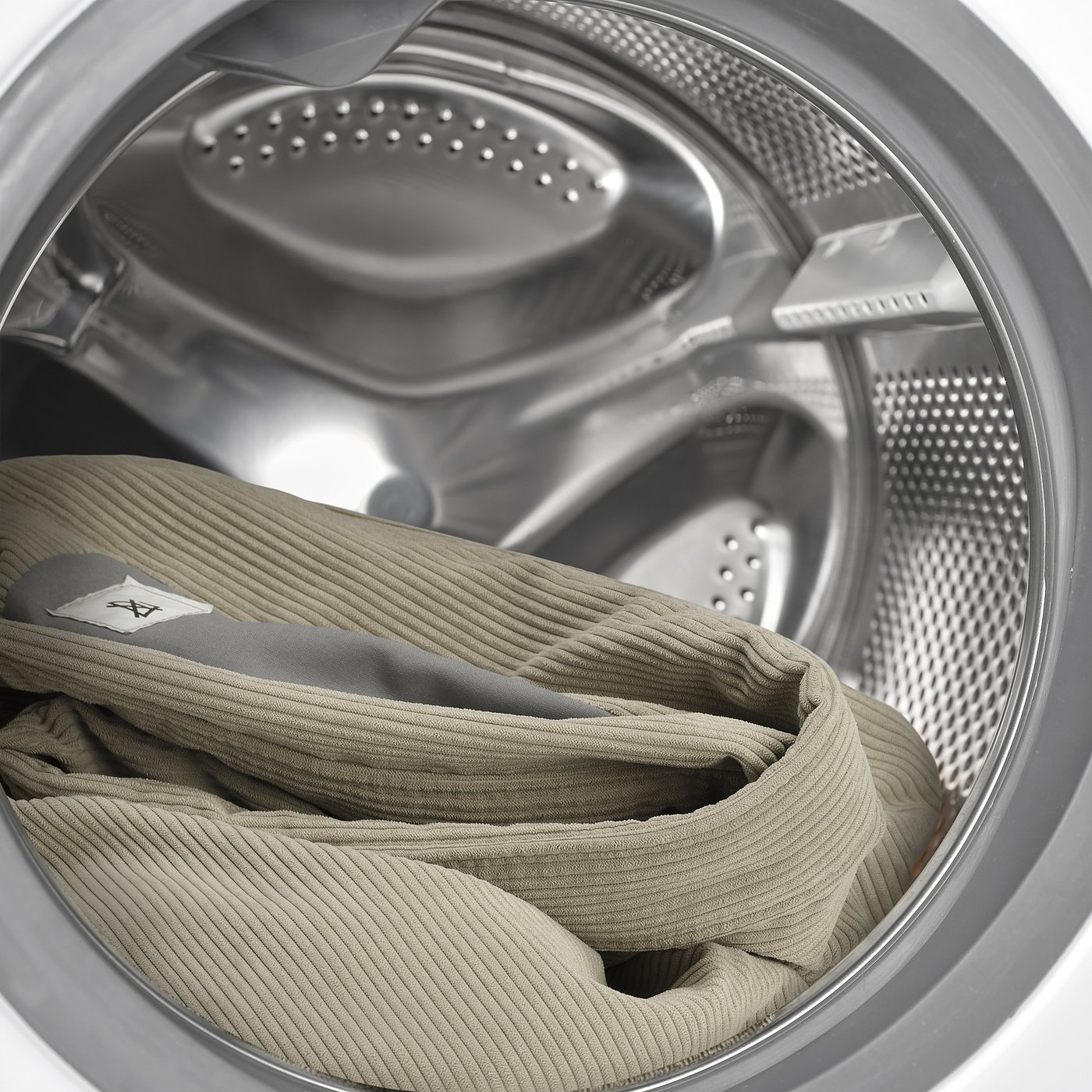 Washed sweater inside dryer, showing machine-washable tag.