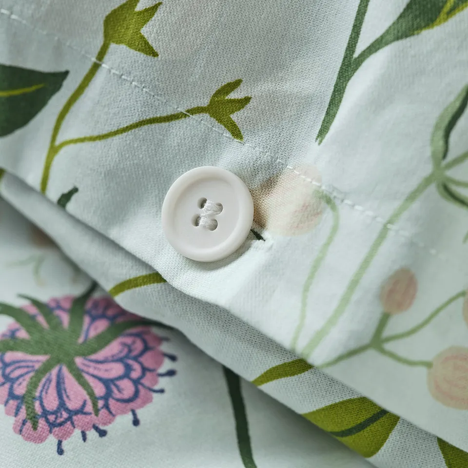 A light blue duvet cover with a floral design, showcasing a button closure detail.