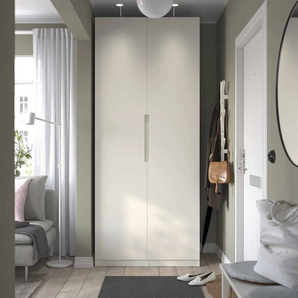 Modern entryway with large white PAX wardrobe, surrounded by cosy grey furniture and wooden floors.