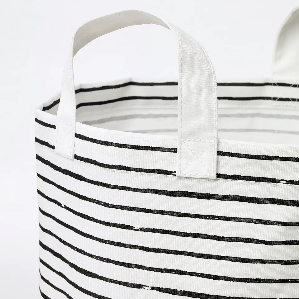 Black and white striped fabric laundry basket with sturdy handles, standing upright.
