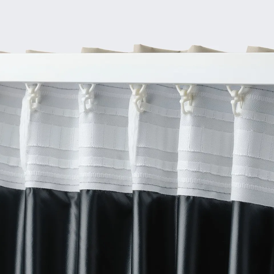 Close-up of white block-out curtains with tabs, beige heading tape, and dark lower section.