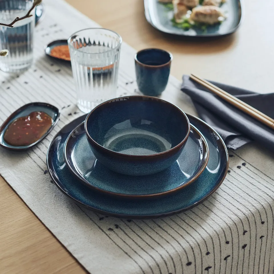GLADELIG blue stoneware set includes plate, bowl, glass. Golden-brown trim. Table setting with chopsticks and sauce.