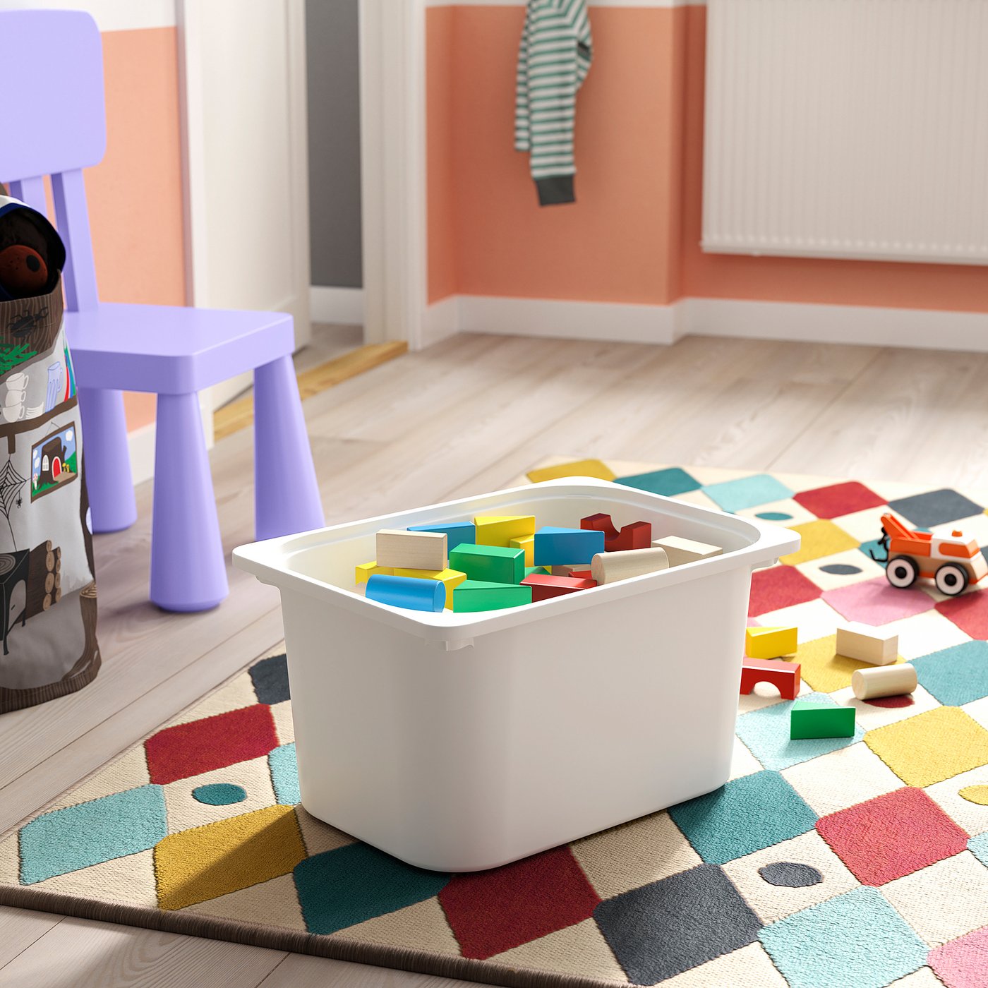 White TROFAST storage box on colourful rug, holding multicoloured toy blocks.