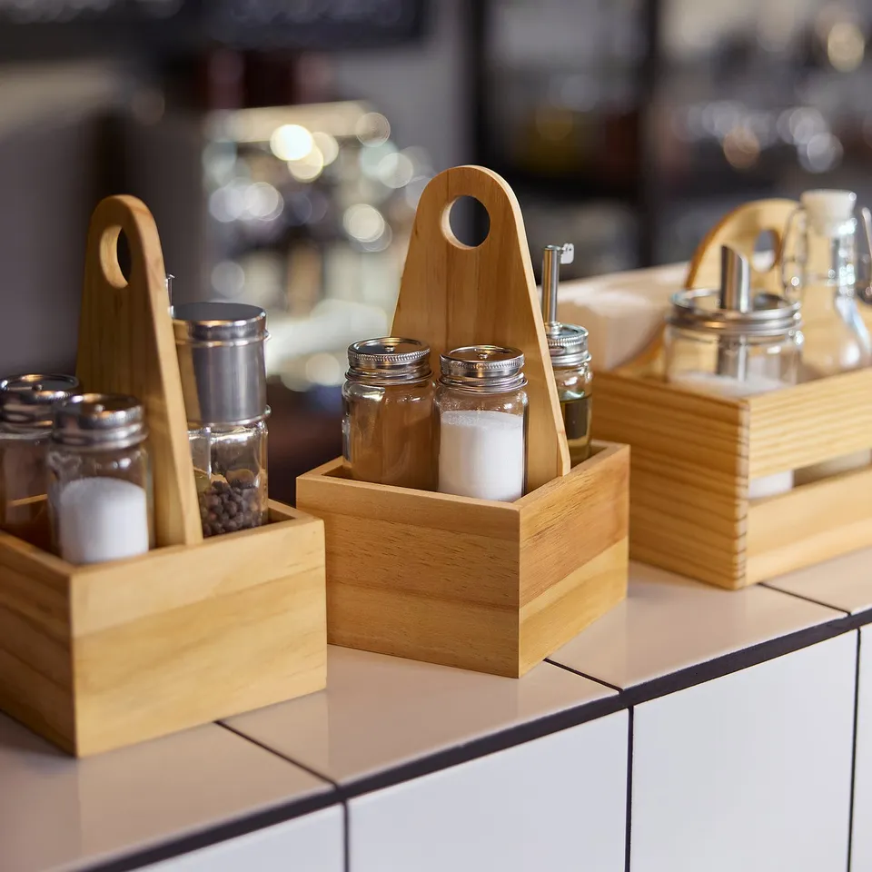 Three wooden spice organisers on white counter; holds jars, small, rectangular, natural wood.