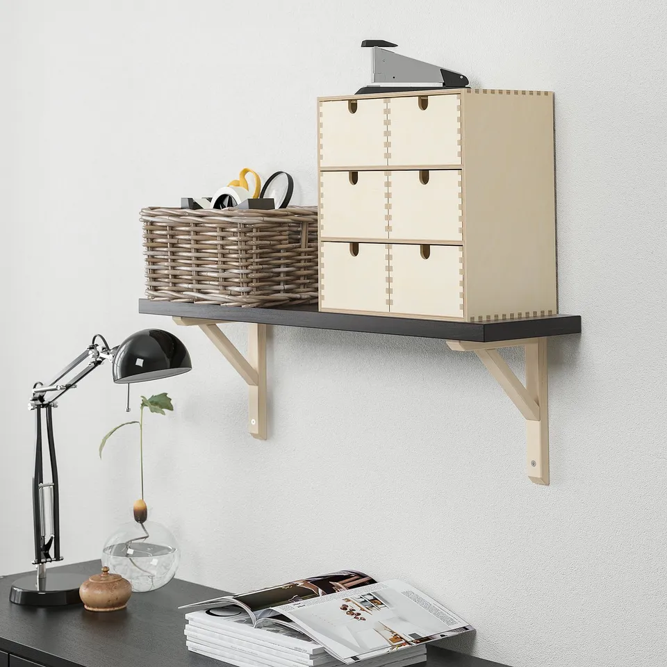 Wall-mounted BERGSHULT shelf with office supplies, plant, and lamp.