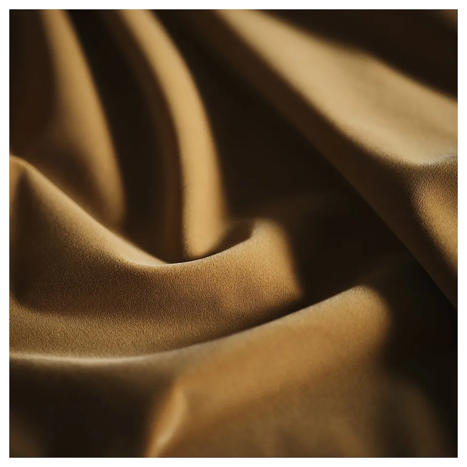 Close-up of luxurious, golden fabric, showcasing smooth texture and rich colour, highlighting high-quality material.