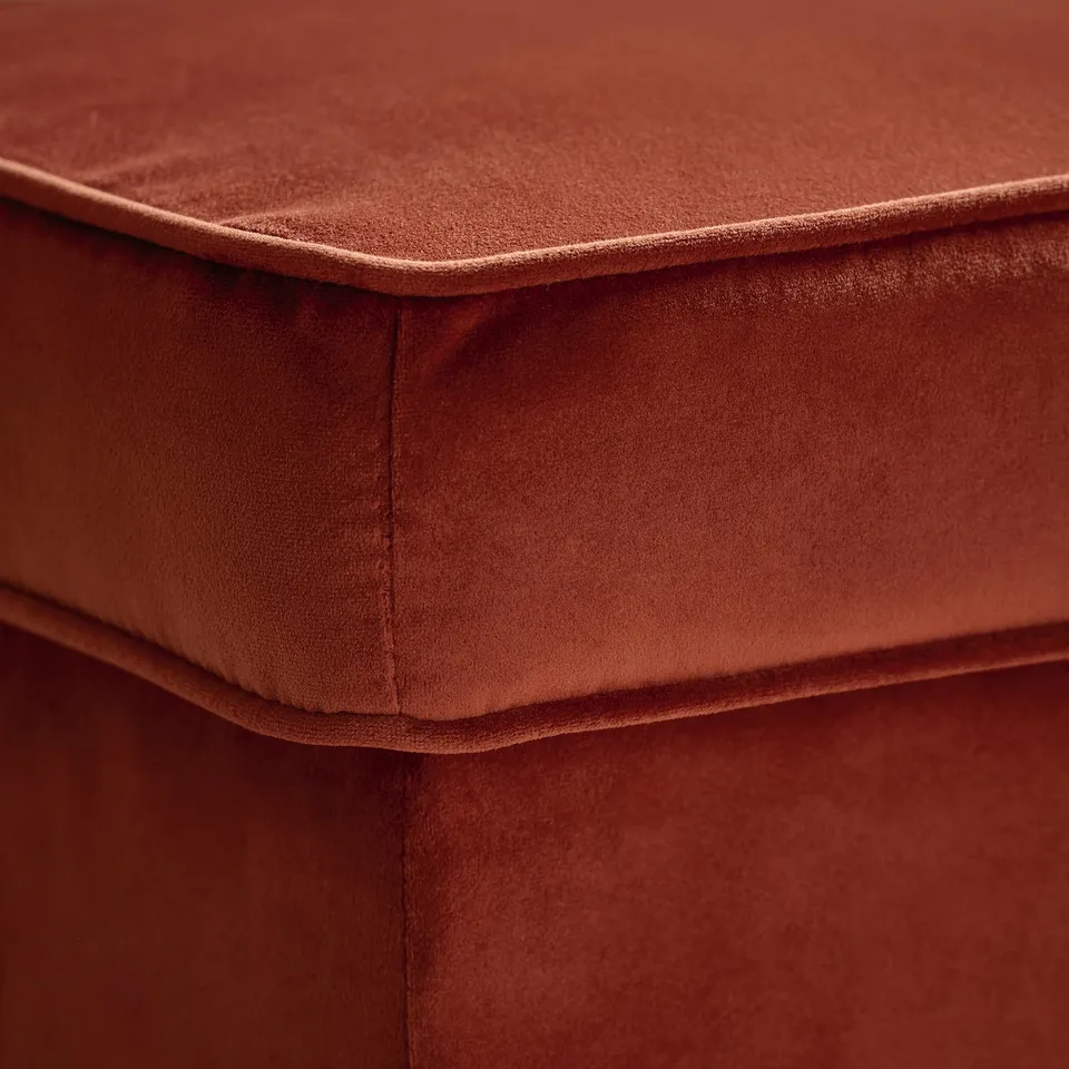 Close-up of a soft, red velour fabric chair, showcasing its smooth texture and precise stitching.