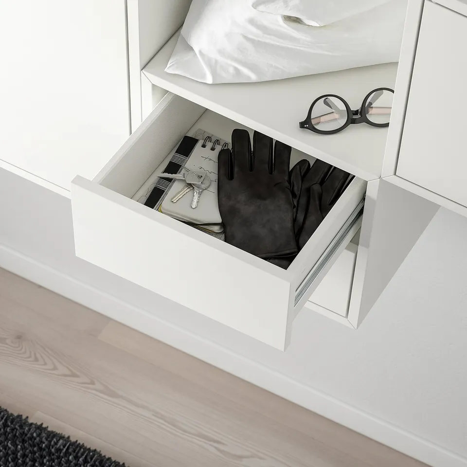 Open EKET storage unit displaying drawer with gloves, keys, and wallet.