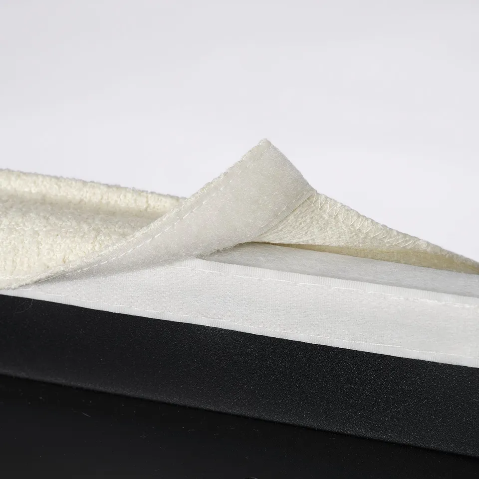 Two white foam cushioning materials stacked. Top piece has textured surface, bottom smooth.