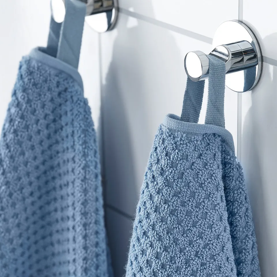 Light blue towels hang neatly on chrome hooks, showcasing soft texture and absorbent material, ideal for everyday use.