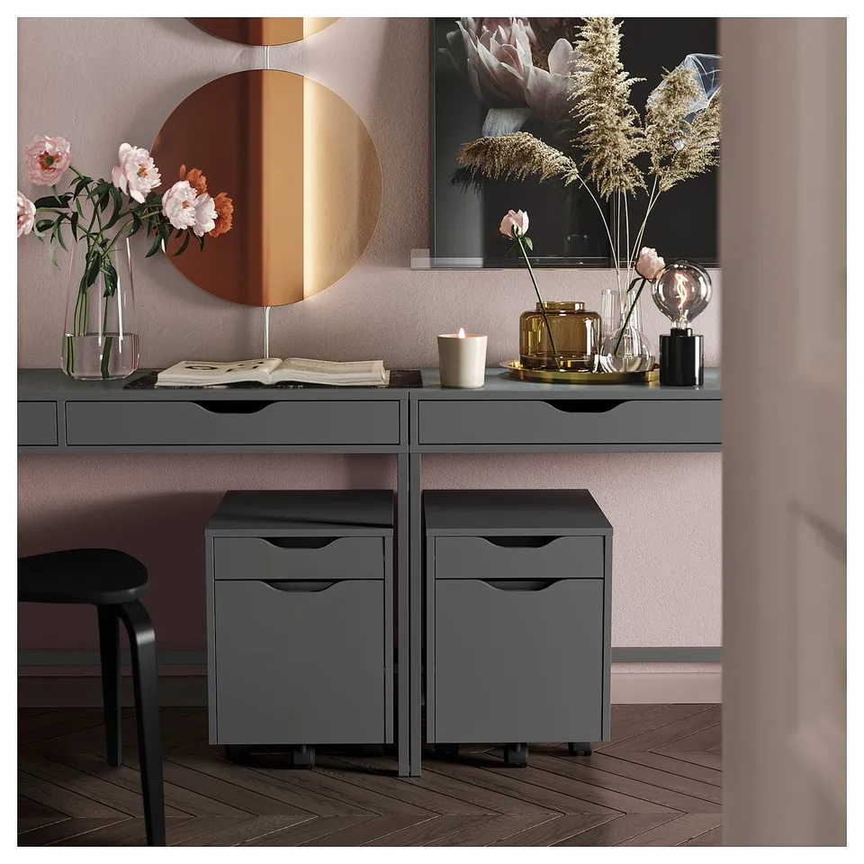 Modern office setup with ALEX dark grey drawers, wooden floor, desk with vases and mirror.