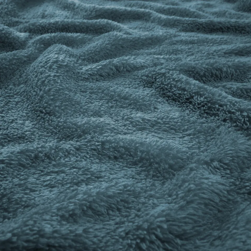 Soft blue fleece bedspread close-up; plush texture visible, showcasing quality and cosiness.