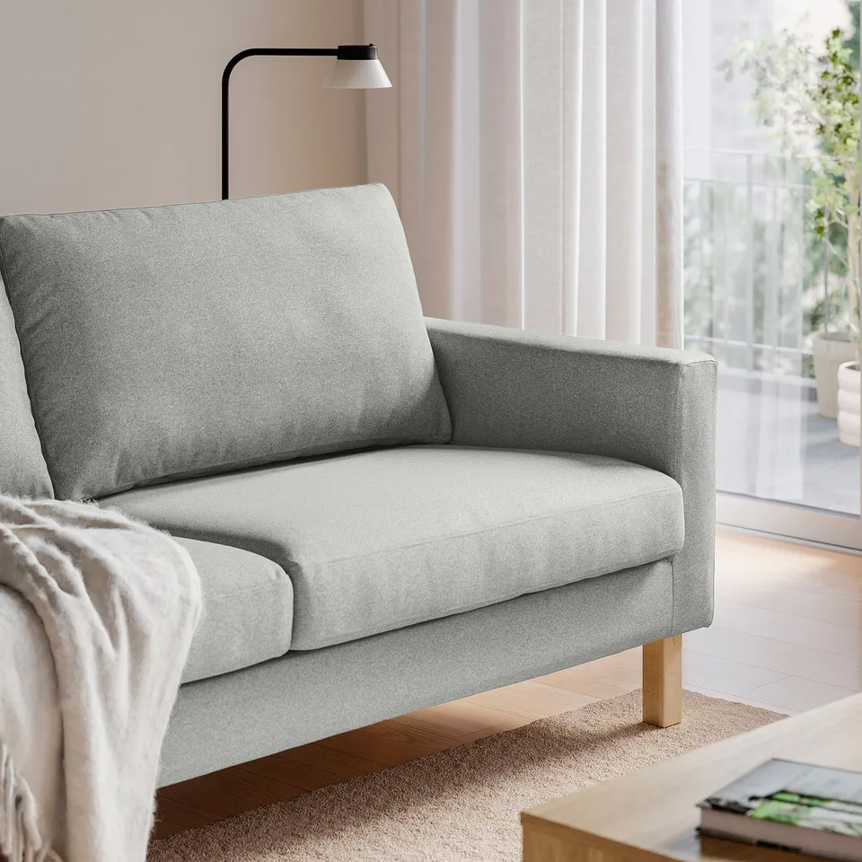 Grey sofa with wooden legs by window, coffee table, lamp.