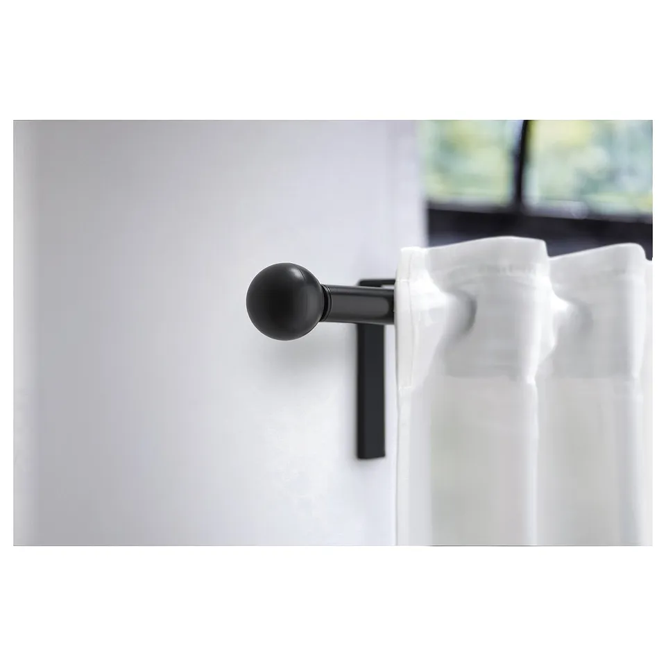 Black spherical finial on rod, modern and minimalist curtain accessory.
