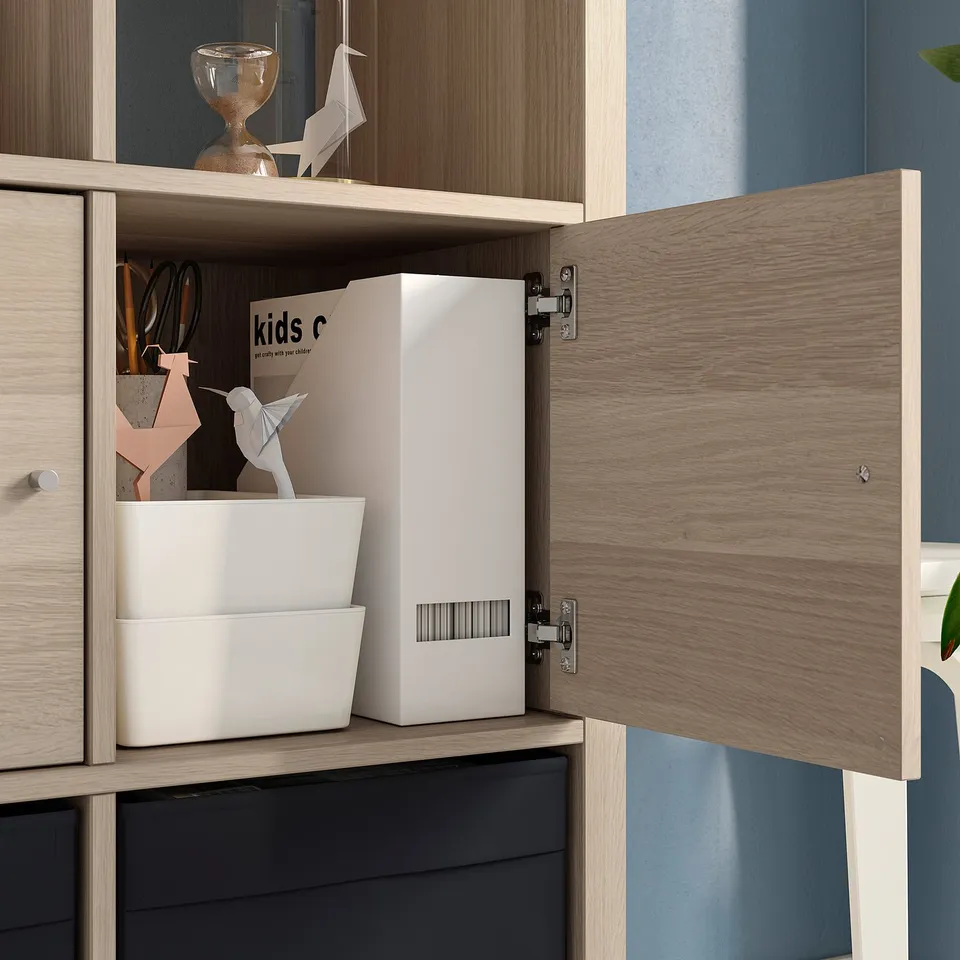 Wooden cabinet with open door showing storage bins and origami papers, including KALLAX label.