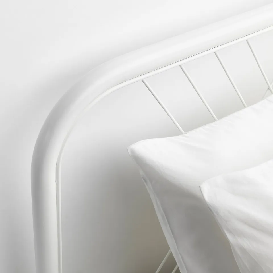 Minimalist white bed frame, clean design. Sturdy steel construction, sleek curved headboard.