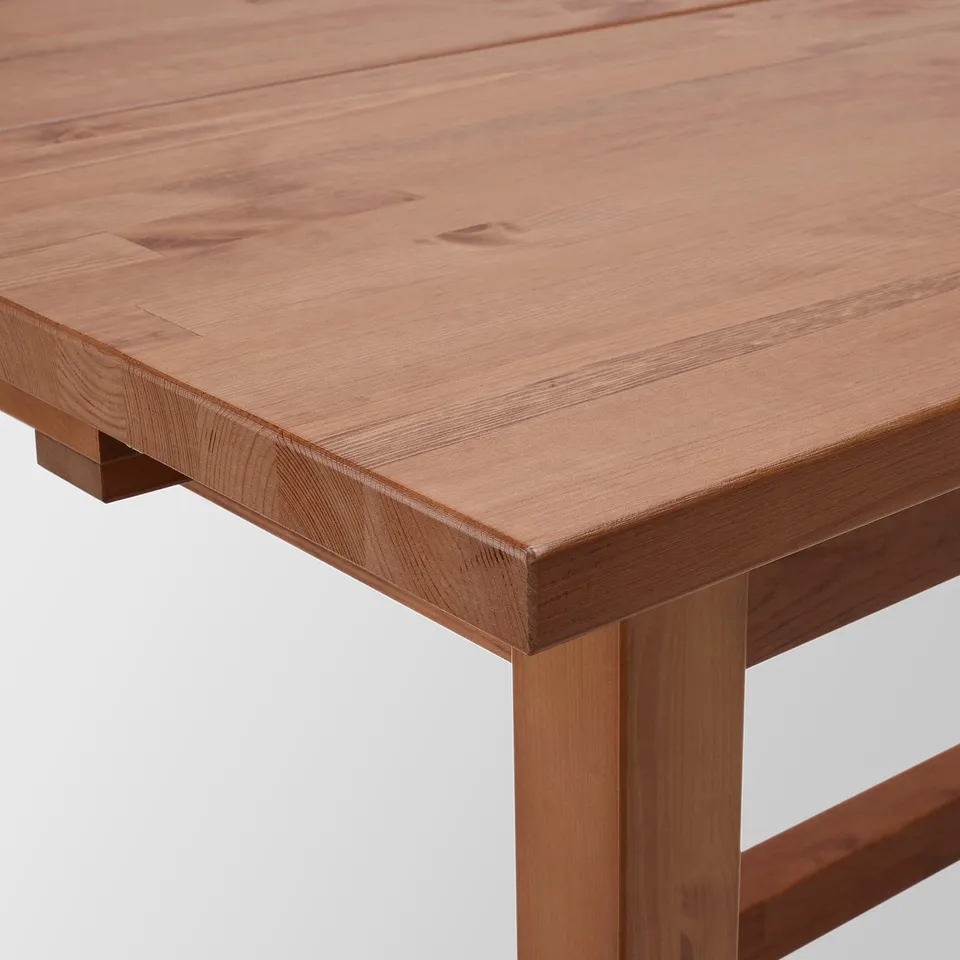Close-up of a smooth, polished wooden table top, showing the grain and light finish.