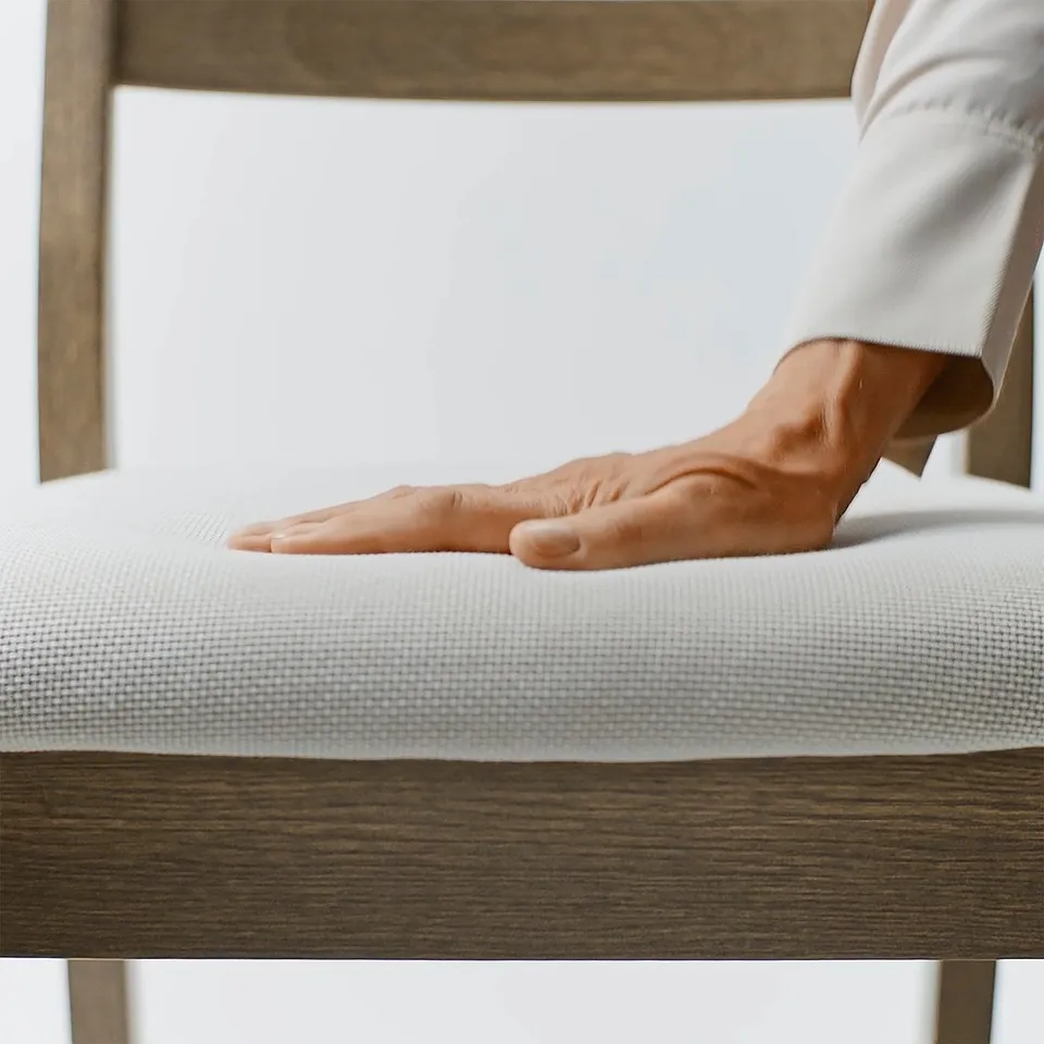 Hand resting on well-crafted, smooth table with sturdy wooden edge. Table top a soft, rounded design, indicating high-quality craftsmanship.