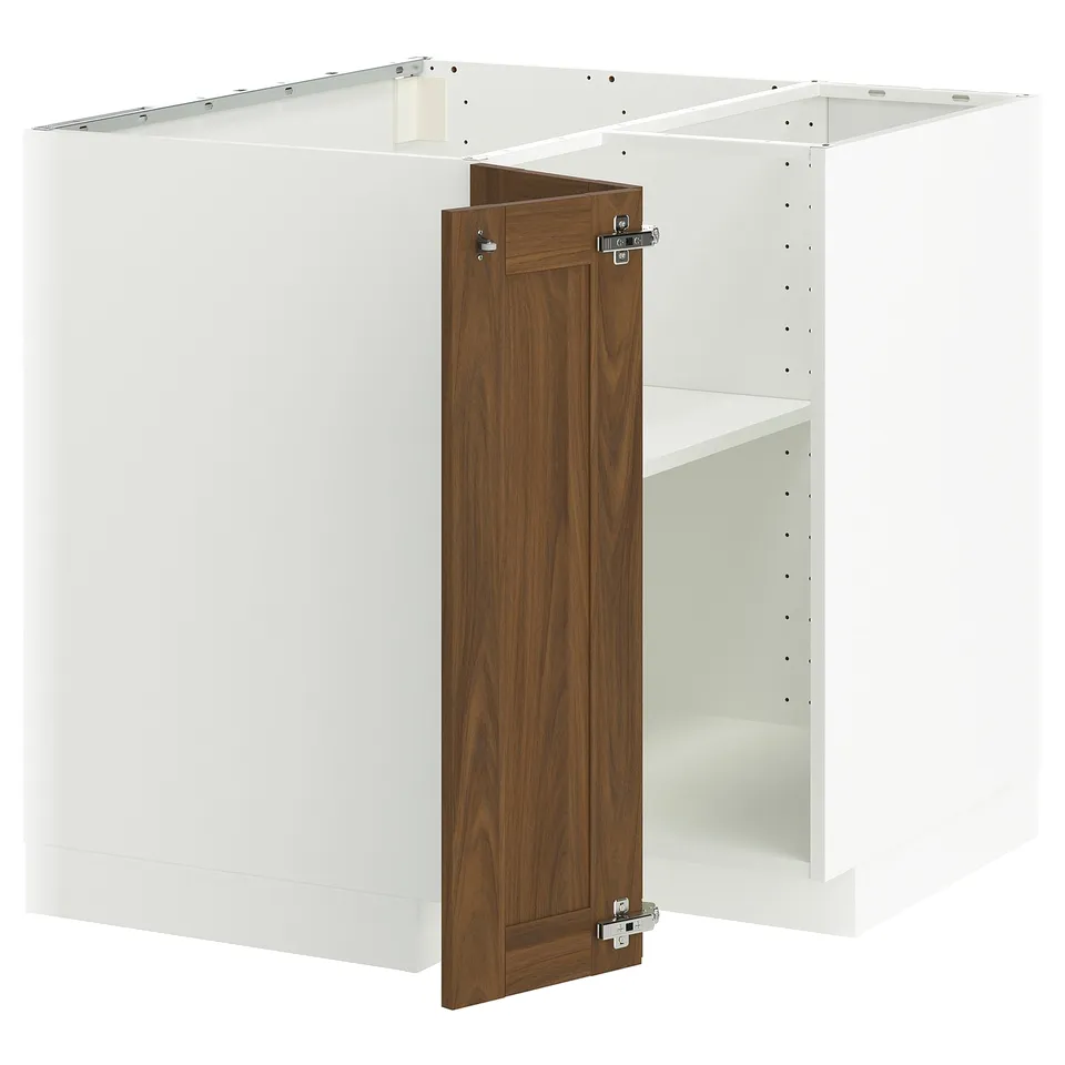 A white METOD kitchen cabinet with a walnut-brown door open. Its a corner base unit with metal hinges.