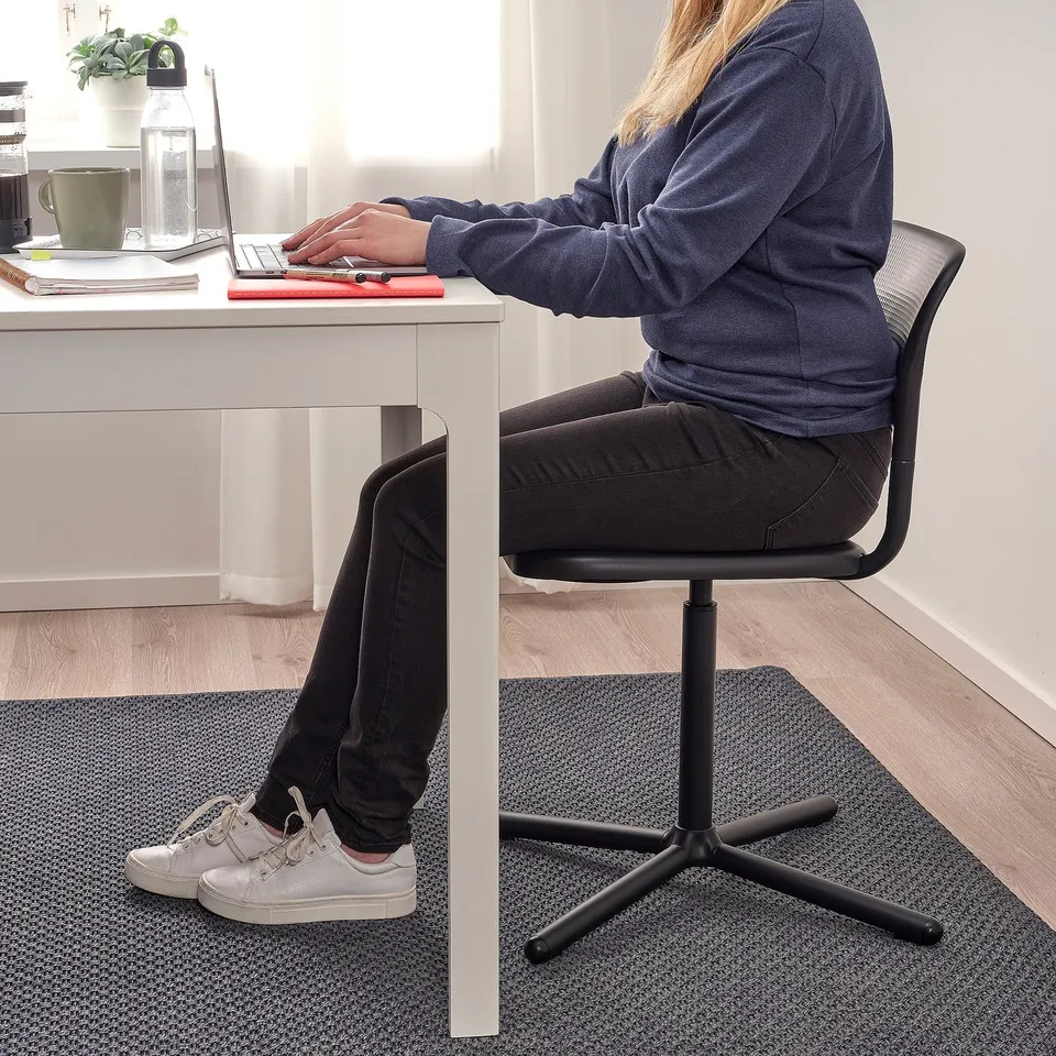 Person sitting at desk on adjustable swivel chair, typing on laptop. The chair has a textured seat and high back for comfort.