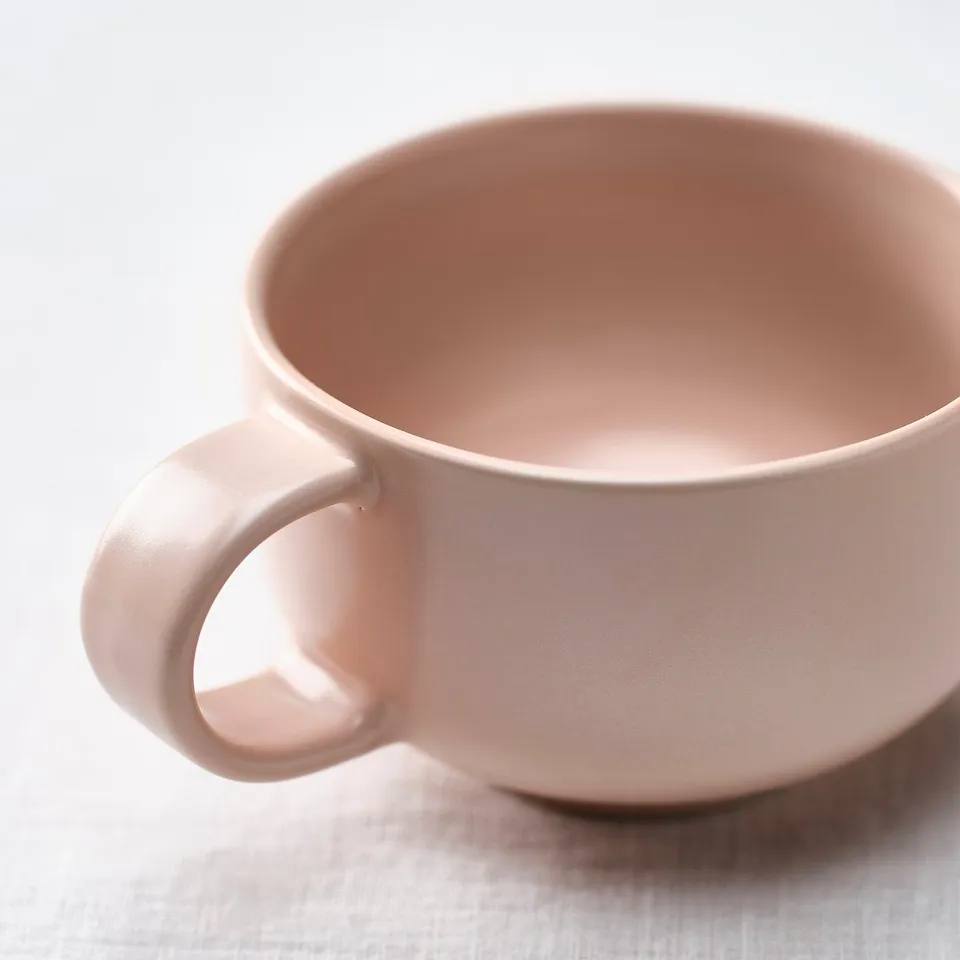 Smooth, light pink stoneware mug with a large, rounded shape and comfortable handle.