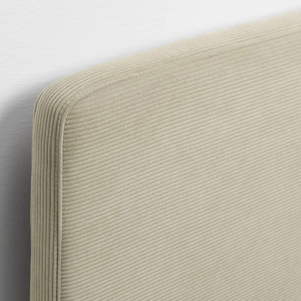 Close-up of a beige bed frames soft, ribbed headboard. Upholstered in breathable, comfortable fabric.