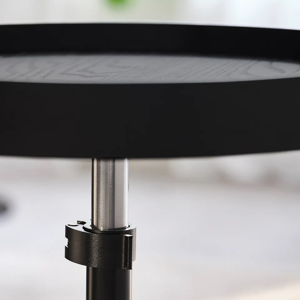 Close-up of adjustable metal pole supporting round wooden table, showing height adjustment feature.