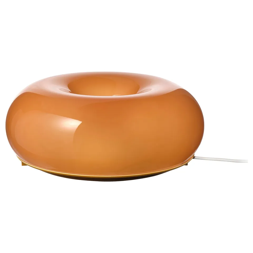 An orange, donut-shaped lamp called värmblixt, with a sleek, modern design and a warm, inviting glow.