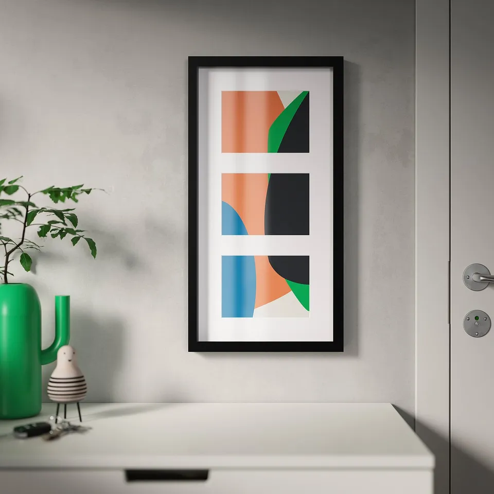Framed triptych art on wall, beside green plant and decor.