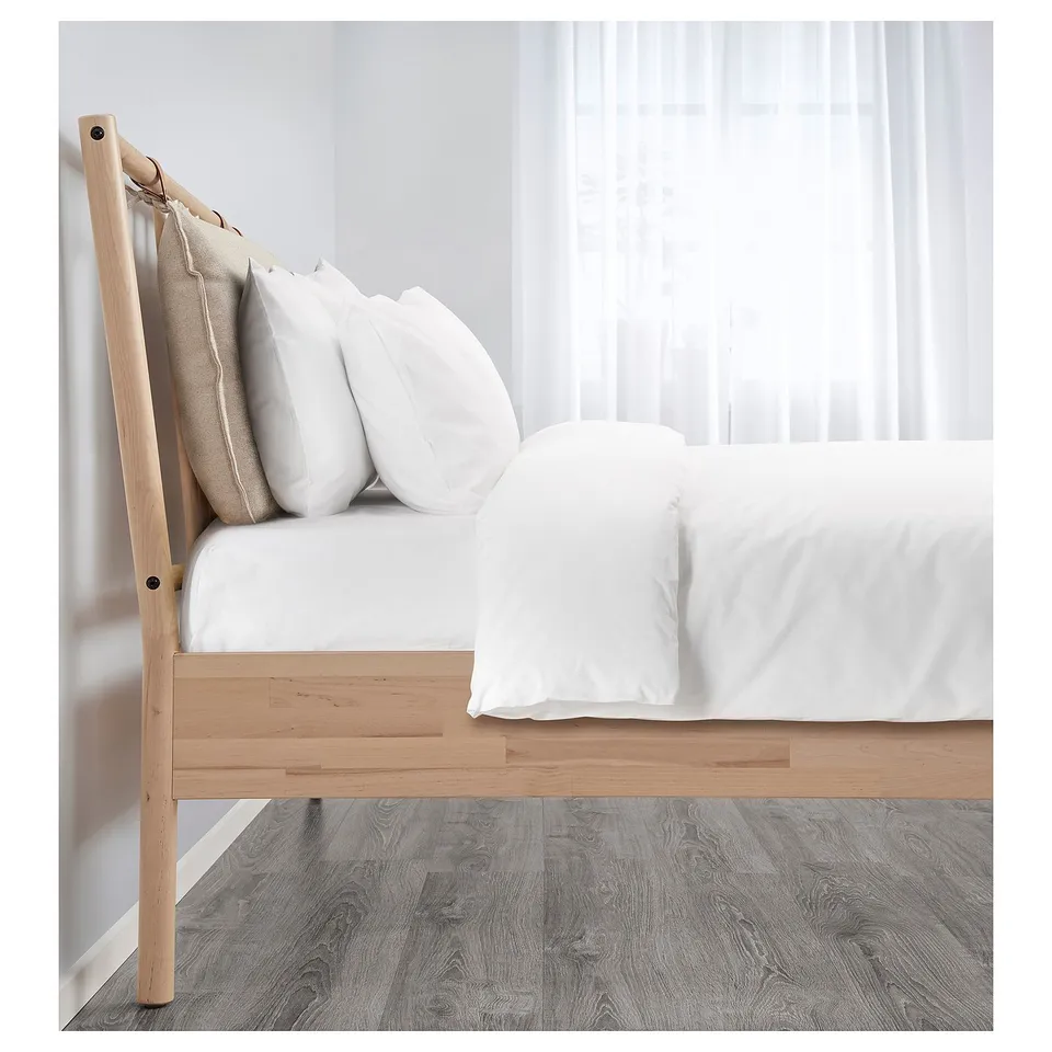 Minimalist wooden bed frame with white linens and pillows, showcasing scandinavian design.