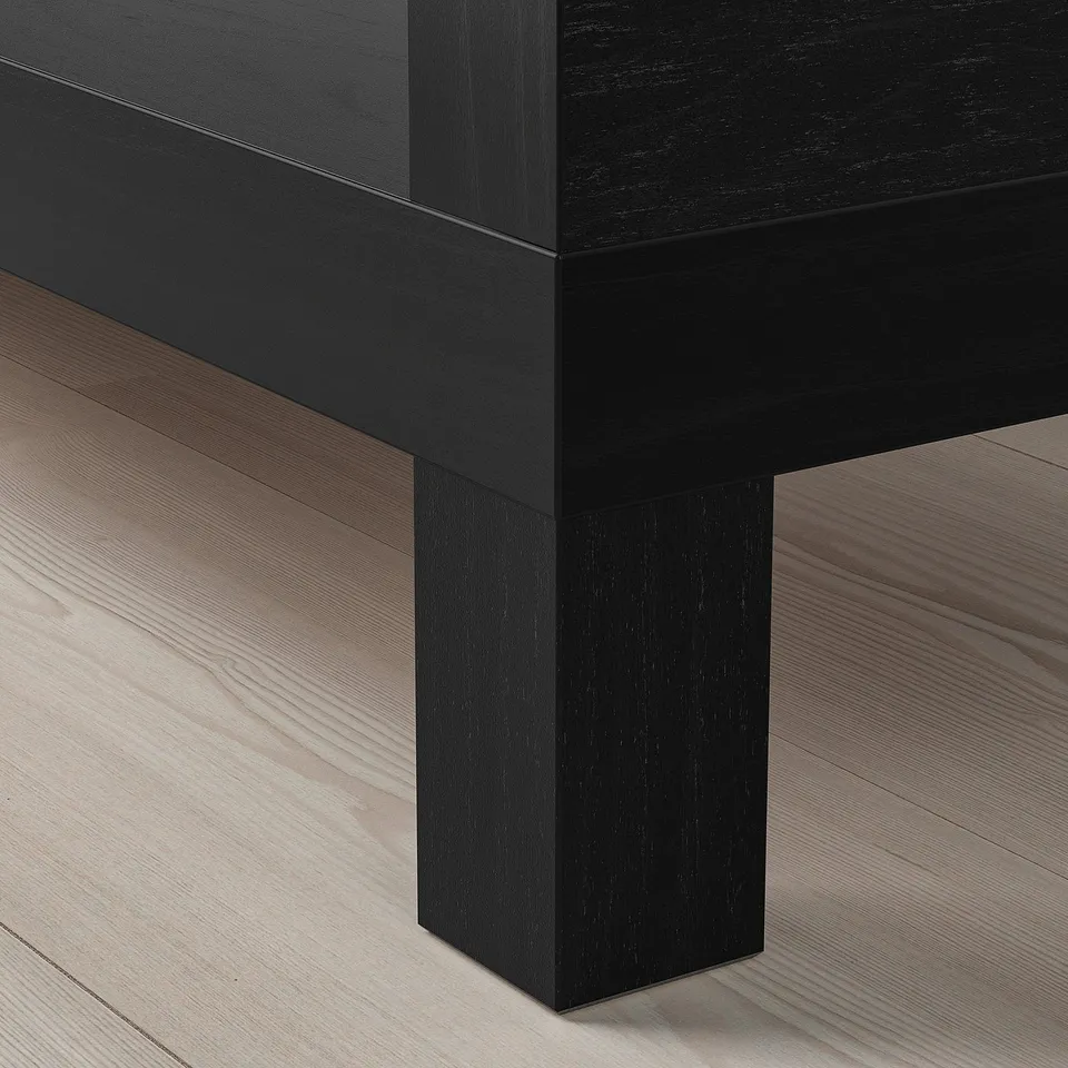 BLACK wooden table leg on light wood floor. Well-crafted, sturdy design.