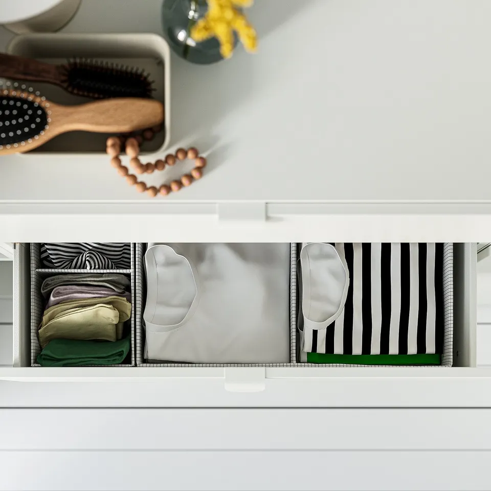 Open white drawer with organised clothes: zebra print top, folded clothes left, automatic drawer closer shown.