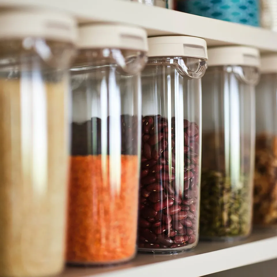 Clear jars with white lids store different types of beans. Jars designed for easy pouring and gripping.