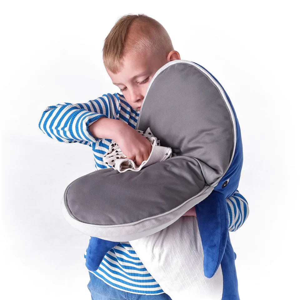 Child hugging a large blue whale stuffed animal, which is soft and safe, part of the BLÅVINGAD collection.